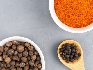 Black pepper, red chili, allspice in white bowl on a gray concrete background. Healthy eating concept