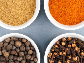Cloves, red chili, allspice, masala in white bowl on a gray concrete background. Healthy eating concept