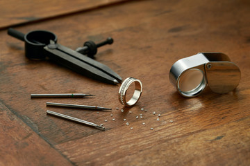 Workplace of a jeweler with tools and equipment for working on an old wooden table. Ready-made...