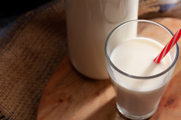 Glass and bottle of milk on wooden board close up