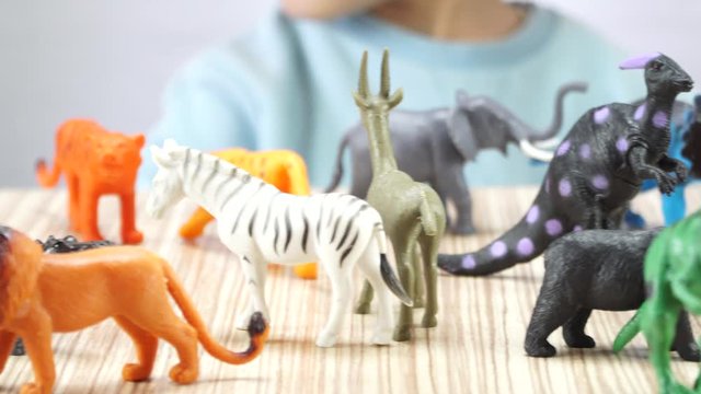 Child plays with plastic animals. 4K