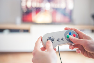Playing retro video games in living room: Close up of a vintage gaming controller holding in hand