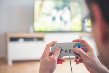Playing retro video games in living room: Close up of a vintage gaming controller holding in hand