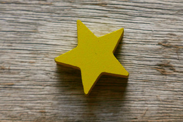 Yellow wooden star shape on wooden background. 