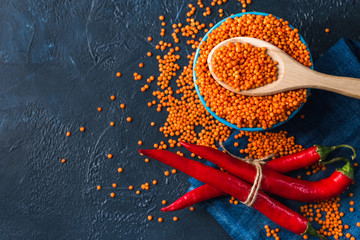 Bowl with red lentil seeds in a classic blue background. Lentil seeds and pepper