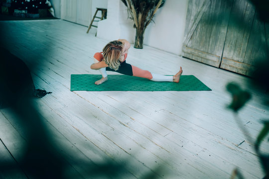 Athletic Adult Female In Sportswear Practicing Yoga Sitting In Bound Side Lunge Pose At Home