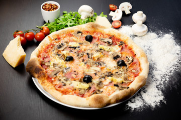 Declicious pizza with ingredients on the side, backed in traditional wooden oven.