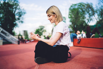 Stylish smiling woman listening to music on smartphone