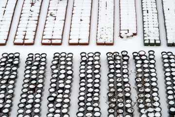 Piled snow on flowerpots arranged in rows.