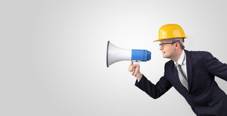 Fototapeta premium Young architect constructor yelling with megaphone and copyspace