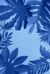 Fototapeta na wymiar Tropical leaves tinted in classic blue color. Handcraft Creative Decorative Floral Frame Made Of Paper Leaves. Flat Lay.
