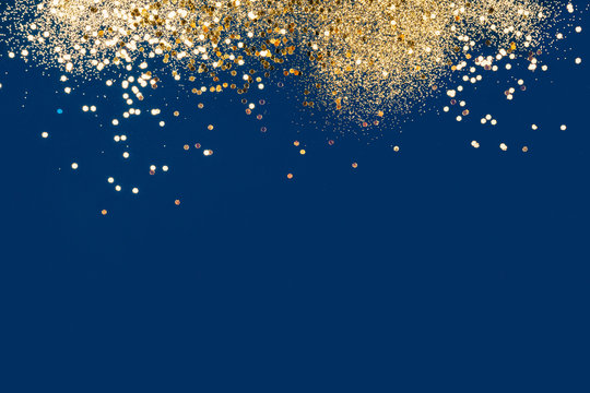 Gold festive confetti on blue background. Beautiful background, space for text. Main color trend concept.