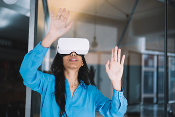 Black woman in blue shirt with VR glasses looking up