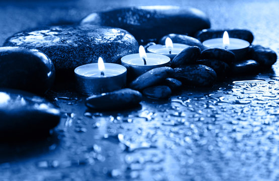 Spa scene. Burning candles and stones tinted in classic blue.