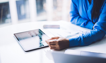 Ethnic businesswoman browsing tablet at workplace