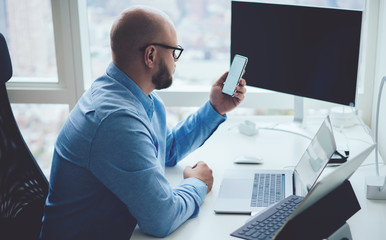 Bald adult businessman using smartphone