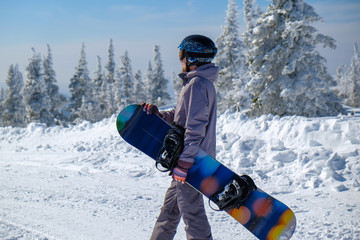 Young snowboarder in the mountains on top. Active rest on a snowboard.