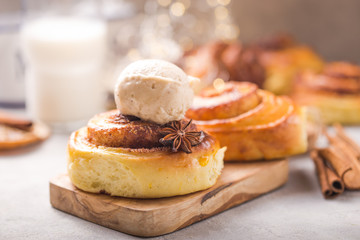 Confectionery baking. Sweet fresh soft roll bun with cinnamon and ice cream on concrete background.
