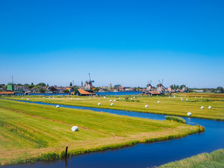 Naklejka premium Landscape with typical dutch windmill village Zaanse Schans in Zaandam, Netherlands. Traditional dutch windmills located by the river Zaan. Culture museum travel and scenery landscape