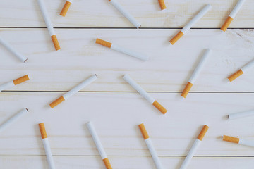 image of several commercially made pile cigarette on white wooden background. or Non smoking campaign concept, idea tobacco pattern top view.