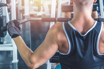 Fototapeta na wymiar Caucasian muscular man using pull down machine in the gym, weight lifting workout.