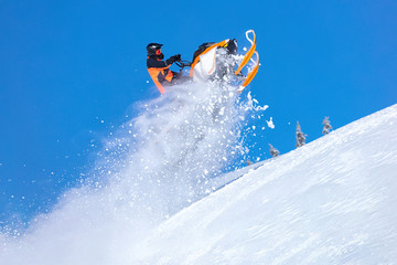 snowmobile jump straight up. the guy is flying and jumping on a snowmobile on a background of blue...