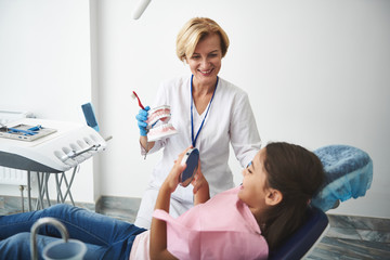 Joyful experienced stomatologist conducting a regular check up