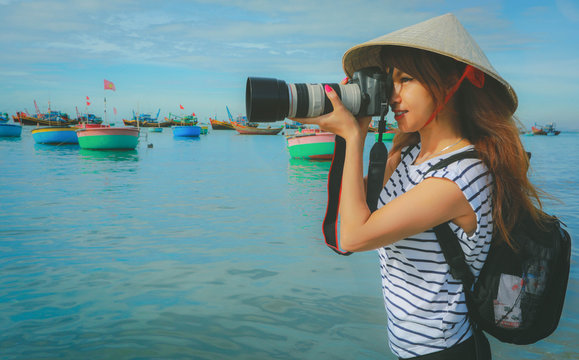 Photographer asian woman taking photos with slr camera professional photography in Mui ne, fishing village with Traditional Vietnamese boats, Vietnam