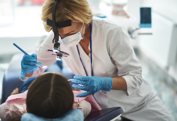Woman is doing dental check-up for young girl