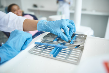 Dentist is using implements for check-up in office