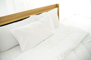 Fototapeta na wymiar Bedroom decorated in minimal style, photograph of white pillows and wooden bed in bedroom 