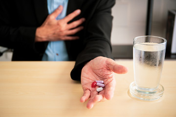 Asian elder businessman taking a medicine, heart attacking on old businessman.  Unhealthy businessman from workaholic concept.