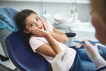 Frightened young lady is having teeth examination