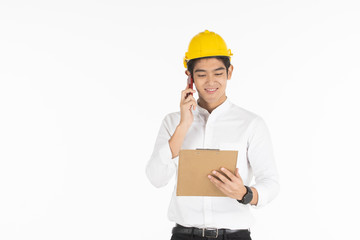 Asian handsome businessman wearing a yellow safety helmet looking and reading a document on a clipboard in his hand close up.