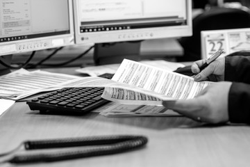 London, England, 28/01/2019 Black and White image of young woman working as a call girl in an administrative role admin work for corporate company in modern office typing on the computer and answering