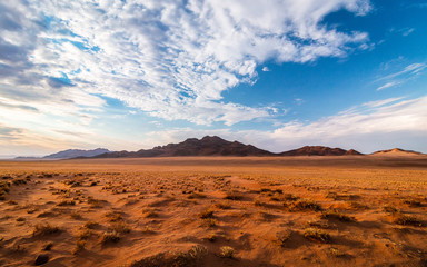 Fototapeta na wymiar Sundowner at the namib desert with fantsastic clouds