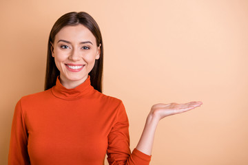 Photo of charming cheerful cute nice attractive manager holding something with her hand showing it to you isolated over beige pastel color background