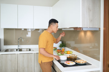 Obraz na płótnie Canvas Happy Asian man preparing food in the kitchen at home.