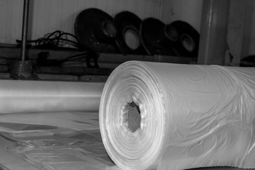 B&W image of a stack of rolled up plastic sheets made in a london factory for mass production plastic packaging. Not very eco friendly however cheap and effective way of packaging or protection