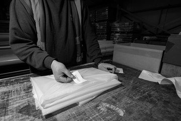 London, England, 28/01/2019 Black & White image of a factory worker labelling plastic wrap product after checking the quality and making sure it's good to send off to clients and customers nationally