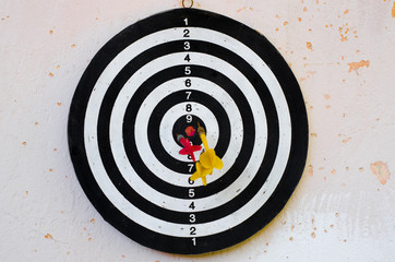 a target with Darts in the center hangs on a battered wall