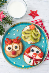 Christmas pancakes in a shapes of deer, tree and snowman made of fresh fruits and berries. Glass of milk. Healthy food for kids ideas. Top view