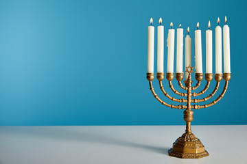 Burning candles in menorah isolated on blue - obrazy, fototapety, plakaty
