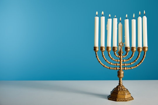 Burning candles in menorah isolated on blue