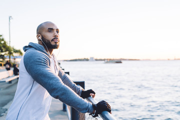 Thoughtful adult black male in sportswear on seafront