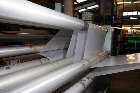 imagery White spool of plastic packaging sheet heavy duty for industrial use outdoors. wrapped around a metal pole ready to feed into a machine for cutting into shape or printing logos.