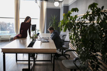 Adult serious man businessman in a business suit discussing business and work with his partner, Secretary beautiful girl and working on a laptop in a modern office.