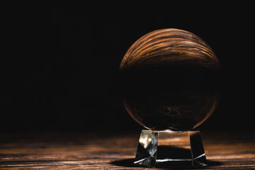 crystal ball on wooden table on black background