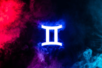 Blue illuminated Gemini zodiac sign with colorful smoke on background