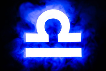 blue illuminated Libra zodiac sign with smoke on background